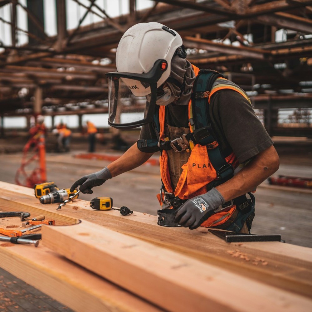 Construction worker measuring wood in a warehouse
